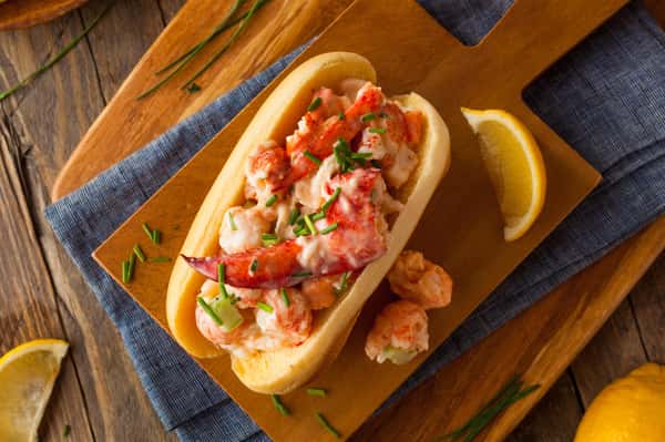 lobster roll on a wooden board with a lemon wedge