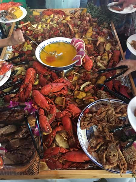 table covered in crawfish, corn, potatoes, bowl of butter