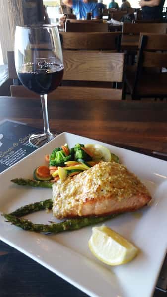 piece of fish with asparagus and steamed vegetables, glass of red wine