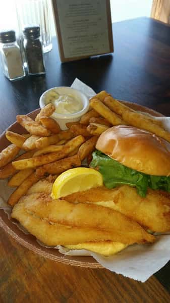 fried fish sandwich on bun with french fries and tartar sauce