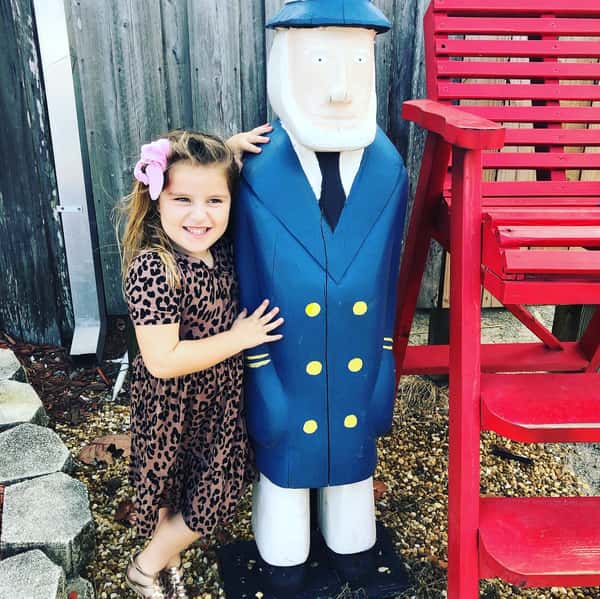 little girl posing with wooden captain