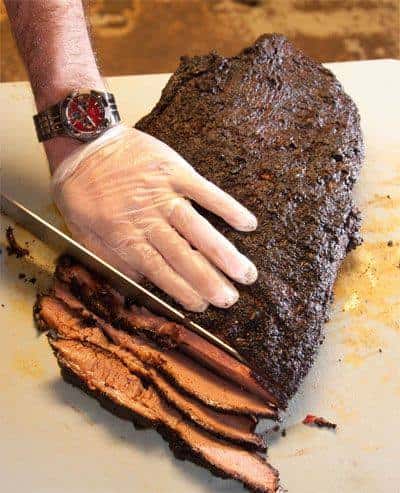 hand holding brisket while being sliced