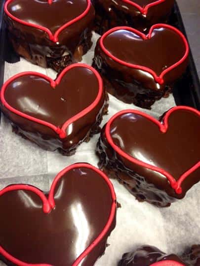 Chocolate cakes in heart shape topped with a red sugar stripe