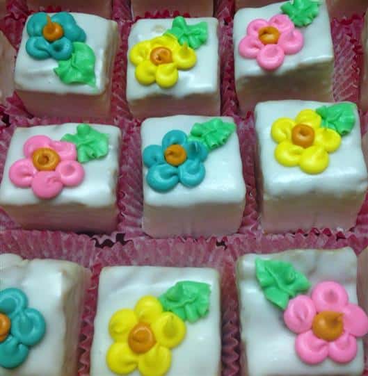 White mini cakes topped with flowers in several colors
