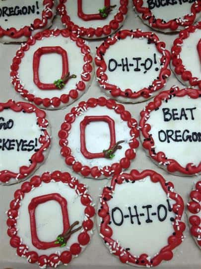 White covered cookies topped red decoration and chocolate letters