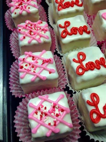 Mini cakes topped with white topping and pink or red decoration