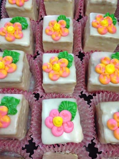 White mini cakes topped with flowers in several colors