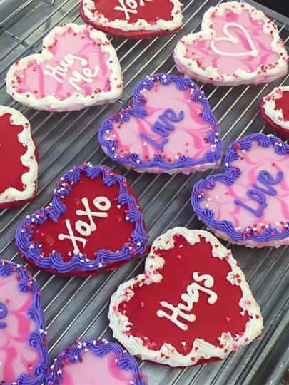Red and pink covered cookies in heart shape topped sugar frosting letters