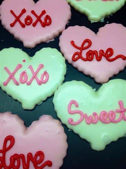 Pink and light green covered cookies topped with letters