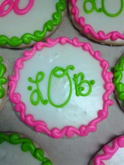 White covered cookies decorated with pink and green letters