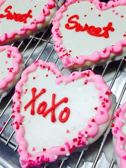 White covered cookies with pink decoration and red letters