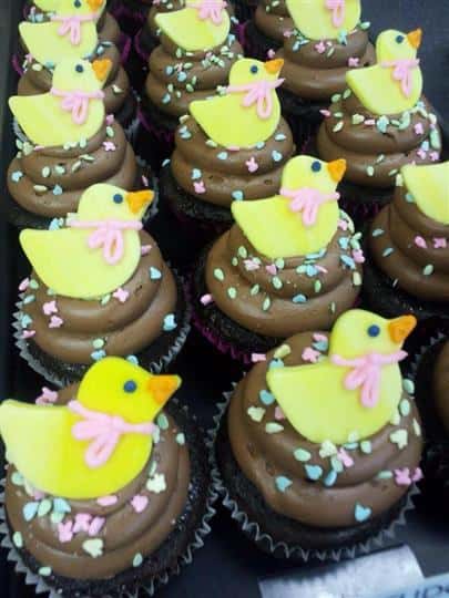 Cupcakes with chocolate frosting topped with little yellow sugar ducks
