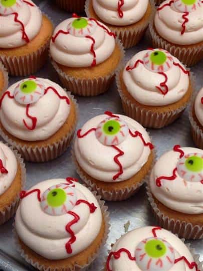Cupcakes with white frosting and a Halloween eye decoration