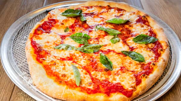Margarita pizza with melted mozzarella, red tomato sauce, and fresh basil leaves on a metal tray.