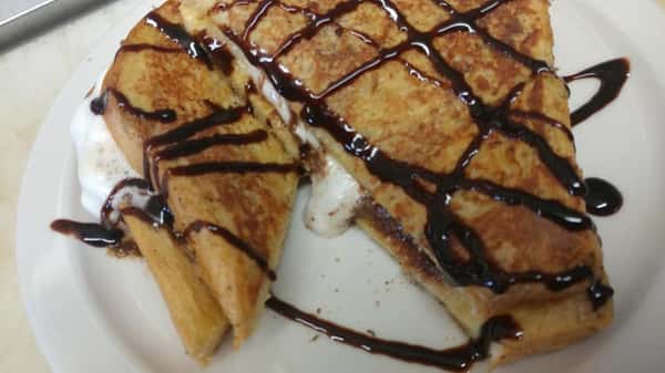 Toasted dessert sandwich filled with marshmallow and chocolate, drizzled with chocolate syrup.