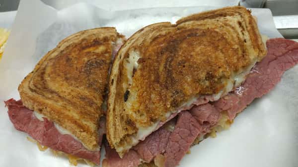 Grilled Reuben sandwich with layers of corned beef, melted cheese, and rye bread.