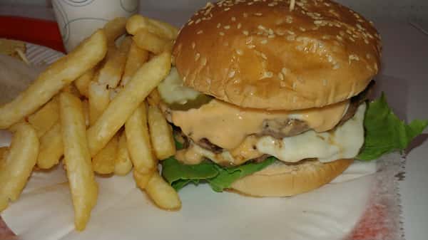 Double cheeseburger with lettuce, pickles, and special sauce on a sesame bun, served with thick-cut French fries.