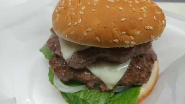 Double cheeseburger with lettuce, onions, and melted cheese on a sesame seed bun.