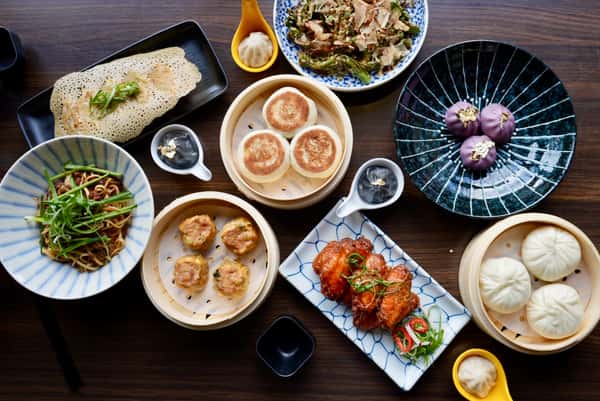 A variety of entrees and sides spread out on a table from Dumpling Time