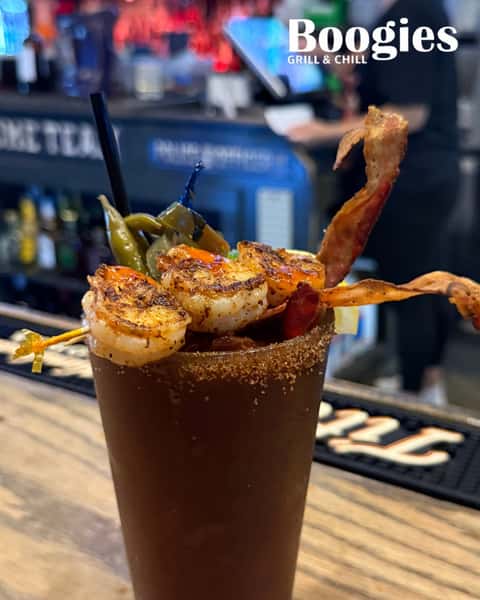 Bold Bloody Mary topped with grilled shrimp, crispy bacon, and pickled vegetables at Boogies Grill & Chill—signature brunch cocktail at a casual American bar.