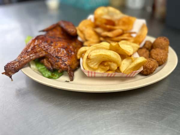 Barbecue chicken quarter with crispy potato curls, thick-cut chips, and golden hushpuppies on a tan diner plate — a comforting BBQ combo.