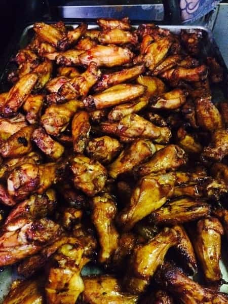 Tray full of smoked chicken wings glazed in barbecue sauce, piled high and ready for serving — perfect for game day or BBQ gatherings.