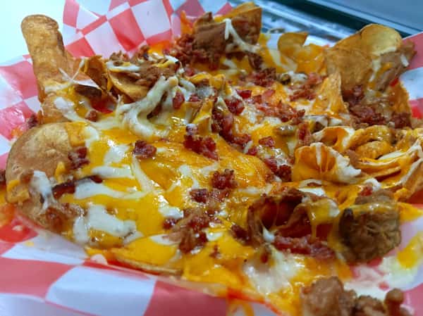 Texas-style BBQ nachos topped with shredded pulled pork, melted cheddar and mozzarella cheese, bacon bits, and crispy house-made chips on a red checkered liner.