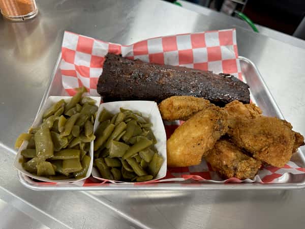 Southern BBQ combo plate featuring smoky pork ribs, crispy fried chicken, and two servings of tender green beans, served on a red checkered tray.