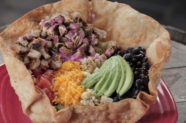 Chicken Fajita Salad, served with cheddar cheese, tomatoes, black beans and avocado. on a bed of romaine lettuce and spring mix. Served in a large crispy flour tortilla bowl.