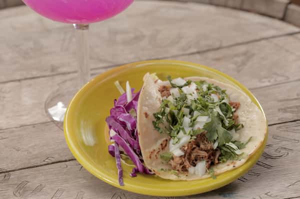 carnitas taco topped with cilantro and onion.