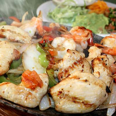 Chicken Fajitas: Marinated in special seasoning and then grilled with onions and bell peppers. Served with lettuce, pico de gallo, crema, guacamole, and flour tortillas.
