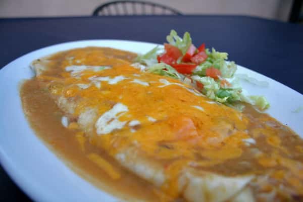 burrito plate topped with sauce and cheese
