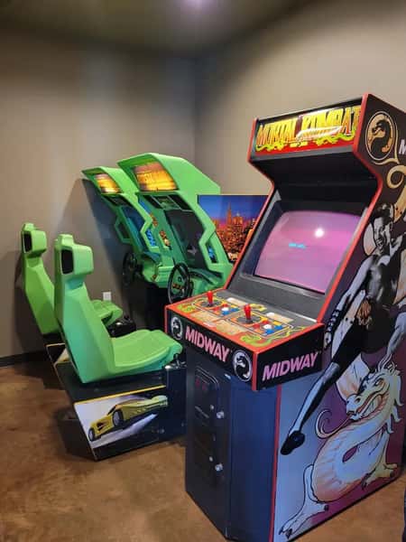 Retro arcade room at Otto's Landing with classic games like Mortal Kombat and racing simulators, adding fun and entertainment for guests of all ages.