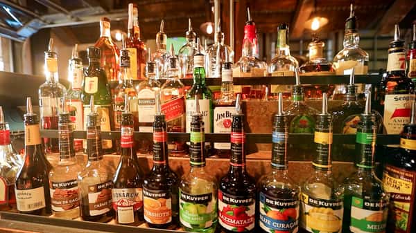 Well-stocked liquor shelf at Otto's Landing featuring DeKuyper liqueurs, Jim Beam, Bushmills, and other premium spirits for cocktails.