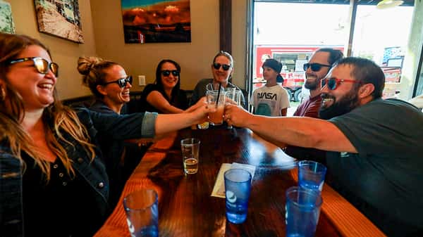 Group of friends laughing and clinking glasses inside Otto's Landing, creating a fun and lively atmosphere for casual dining and drinks.