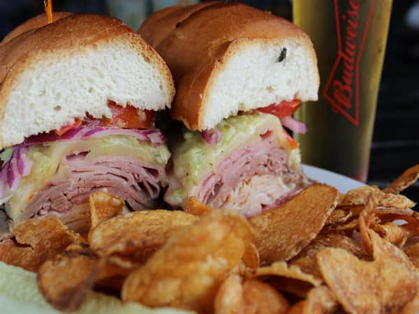 sandwich with salami, ham, turkey, and roast beef with a side of chips