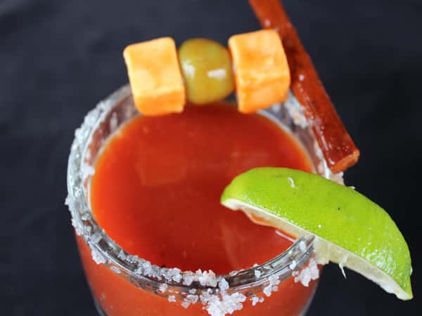 bloody mary topped with lime, salt, olives, beef jerky and cheese