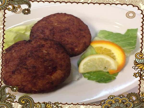 Two homemade crabcakes with two lemon wedges