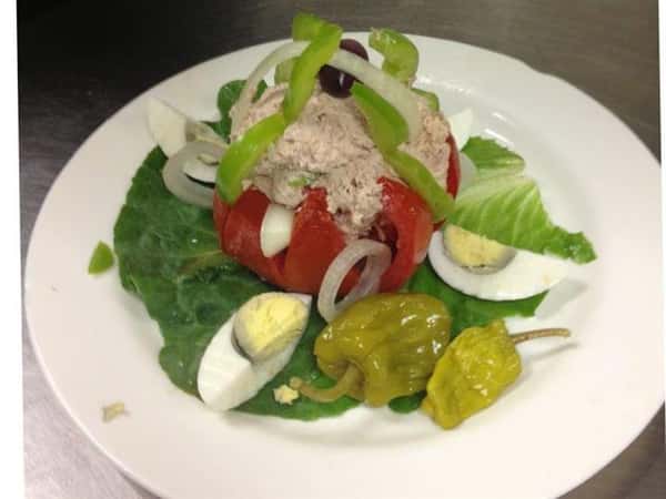 a greek salad with hard bouled eggs, onions, feta cheese, black olives, onion, green pepper and a pepperoncini