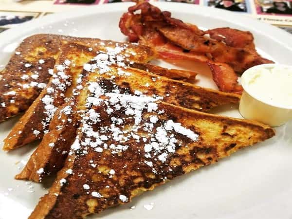 french toast topped with powdered sugar served iwth bacon