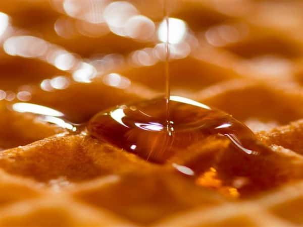 close up of waffle with syrup being poured