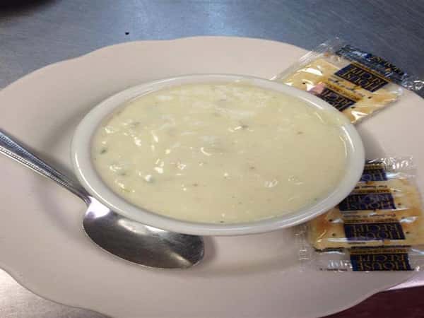 new engalnd clam chowder in a white bowl with crackers on the side