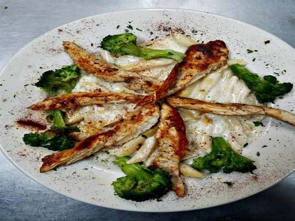 penne pasta with alfredo sauce served with broccoli and cajun chicken breast strips