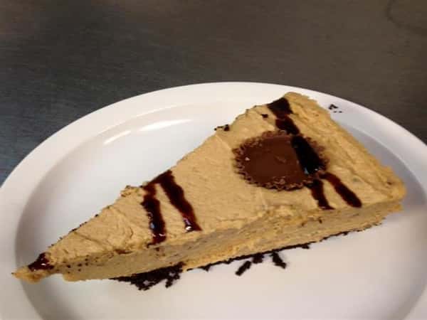 peanutbutter cheesecake drizzled with cholate sause and a peanut butter cup on top