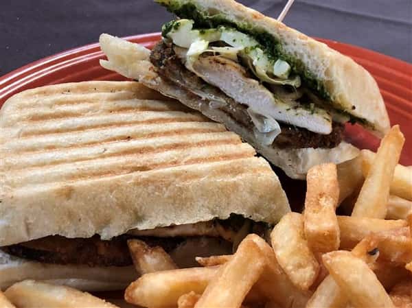 a panini with grilled chicken and pesto with a side of french fries