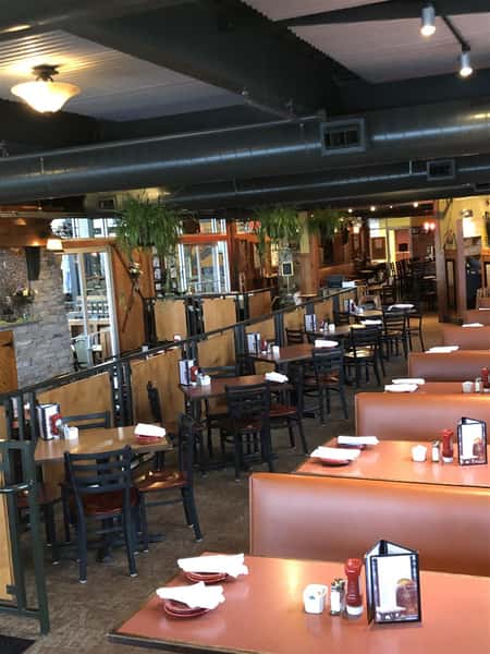 indoor seating area with booths and tables with four chairs per table with place settings