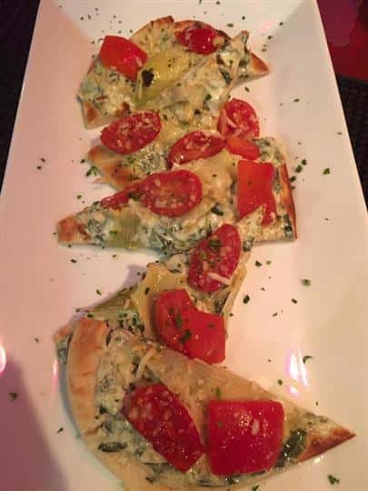 a flatbread cut into five pieces with creamed spinach and red pepper on top