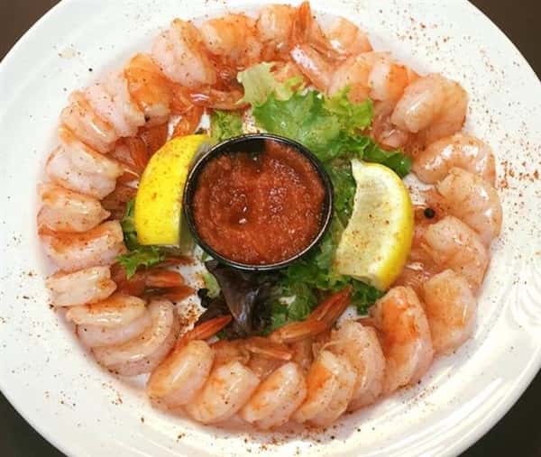 shrimp cocktail with dipping sauce and two lemon wedges