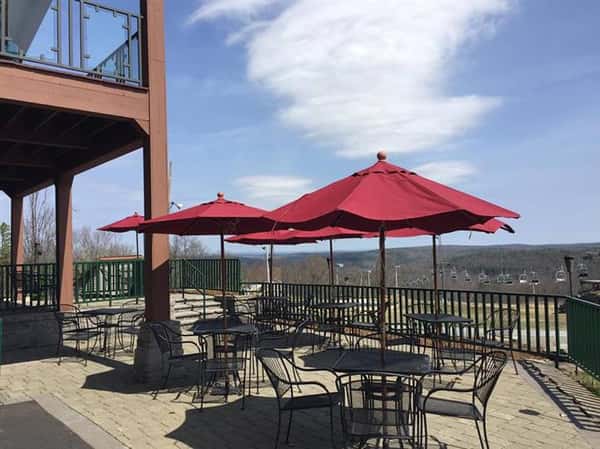 outdoor seating area of six tables with four chairs at each tables with six red umbrellas
