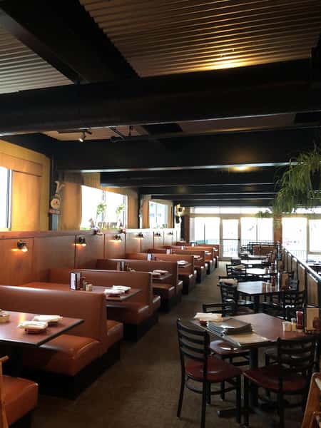 indoor seating area with booths and tables with four chairs per table with place settings